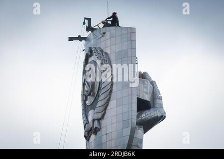 Kiew, Ukraine. 21. Juli 2023. Arbeiter werden dabei beobachtet, wie sie sich darauf vorbereiten, das sowjetische Wappen vom Schild der Mutterland-Skulptur in Kiew zu demontieren. Bis Ende August 2023 planen die ukrainischen Behörden, den ukrainischen Dreizack anstelle des sowjetischen Wappens auf dem Schild der berühmten Statue zu installieren. Die Ukraine führt seit 2014 eine aktive Dekommunisierung durch und verweigert die Namen, Symbole und Ideologie der Sowjetära in allen Lebensbereichen. (Foto: Oleksii Chumachenko/SOPA Images/Sipa USA) Guthaben: SIPA USA/Alamy Live News Stockfoto