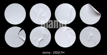 Ein Satz leerer, weißer, runder, selbstklebender Papieraufkleber, isoliert auf schwarzem Hintergrund. Stockfoto