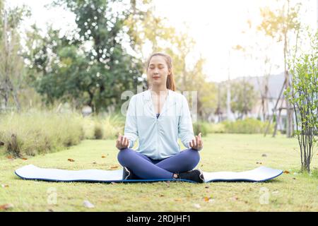 Asiatische Frau, die Lotus-Yoga-Position draußen im Garten macht Stockfoto