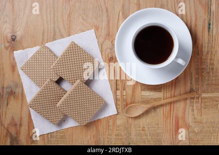 Eine Tasse Kaffee und quadratische Waffeln auf altem Holzhintergrund, Blick von oben Stockfoto