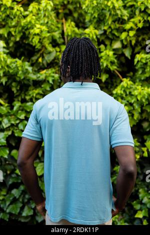 Rückansicht eines afroamerikanischen Mannes mit Dreadlocks in blassblauem Poloshirt im Garten Stockfoto