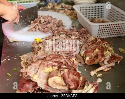 ZAOZHUANG, CHINA - 22. JULI 2023 - Ein Koch Schneidet ein gekochtes Lamm in einem Hammelsuppenrestaurant in Xiji, Shanting District, Zaozhuang City, East China's Stockfoto