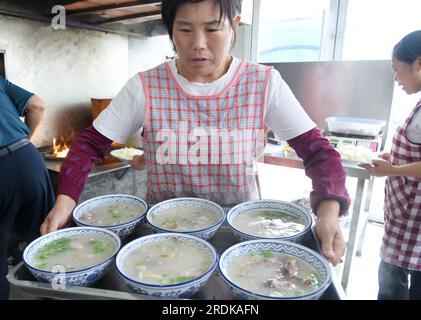 ZAOZHUANG, CHINA - 22. JULI 2023 - Ein Kellner serviert Hammelsuppe in einem Restaurant für Lammsuppen in Xiji, Shanting, Zaozhuang, Ostchina Stockfoto