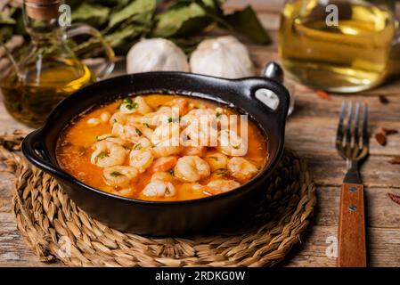 Schwarzer Auflauf mit Knoblauchgarnelen oder Pil-Pil auf einem rustikalen Holztisch. Stockfoto