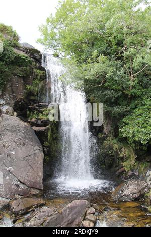 Ein hoher Wasserfall, der über einem Hillside Rock Face kaskadiert. Stockfoto