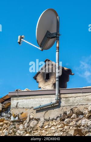 Ein alter Rauchschornsteintopf und eine moderne Satellitenschüssel zum Empfangen von Fernsehsignalen. Kontraste. Pacentro, Provinz L'Aquila, Abruzzen, Ital Stockfoto