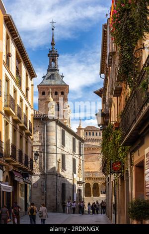 Segovia, Spanien, 03.10.21, Calle de Juan Bravo, enge mittelalterliche Straße in Segovia und Glockenturm Iglesia de San Martin. Stockfoto