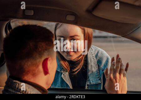 Ein Mädchen, das sich vor der Reise durch ein Autofenster von dem Jungen verabschiedet Stockfoto