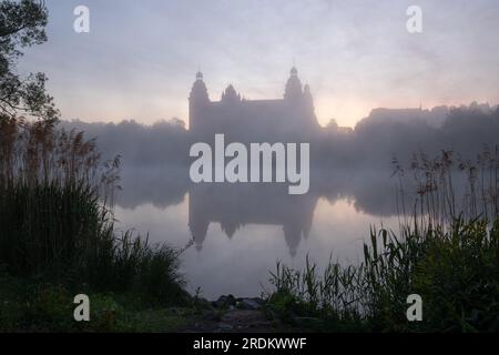 Majestätischer Sonnenaufgang: Schloss Johannisburg in Aschaffenburg, Main River. Ein atemberaubendes Spektakel, wenn die Morgensonne durch den ätherischen Nebel dringt Stockfoto