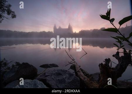 Majestätischer Sonnenaufgang: Schloss Johannisburg in Aschaffenburg, Main River. Ein atemberaubendes Spektakel, wenn die Morgensonne durch den ätherischen Nebel dringt Stockfoto