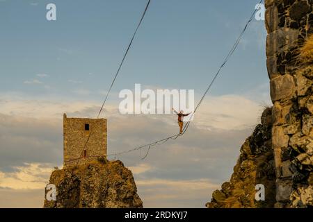 Rovensko Pod Troskami, Tschechische Republik. 21. Juli 2023. Slackliner durchquerten die 100 Meter lange Strecke zwischen den Türmen Baba und Panna der Ruinen des Troskjakschlosses in Rovensko pod Troskami, Region Semily, Tschechische Republik, mit einem Seil, das am 21. Juli 2023 in einer Höhe von 50 Metern befestigt wurde. Fans des Sports Slackline, modernes Seilwandern, demonstrierten hier im Rahmen der Wochenendveranstaltung Lanochodci na Troskach ihre Fähigkeiten. Die sogenannte Grand Virgin Line, die sich über Trosky erstreckt, ist eine der längsten und schönsten in der Tschechischen Republik. Kredit: Radek Petrasek/CTK Photo/Alamy Live News Stockfoto