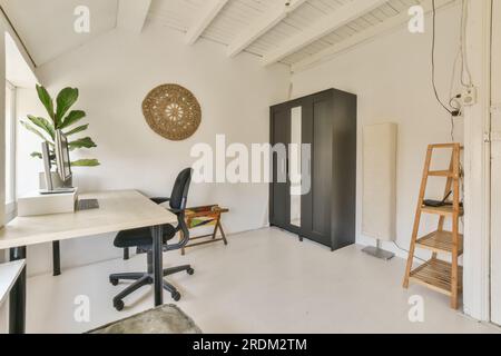 Ein Bürobereich mit weißen Wänden und Holzfußboden der Raum verfügt über eine Holzleiter, die an die Wand lehnt Stockfoto