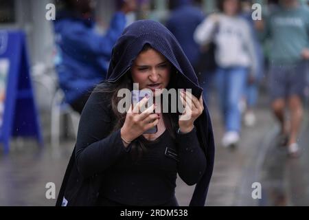 London UK. 22. Juli 2023 Eine Fußgängerin in der Wimbledon High Street bedeckt ihren Kopf bei Regenschauern. Credit amer Ghazzal/Alamy Live News Stockfoto