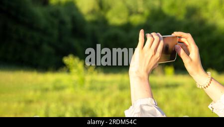 Hände halten Mobiltelefon und fotografieren im Freien. Bannerhintergrund. Stockfoto