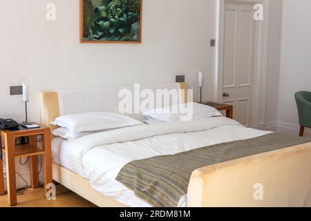 Zimmereinrichtung mit großem einfach hergestelltem Bett. Stockfoto