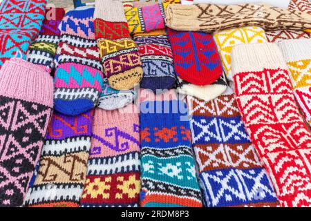 Reihen handgestrickter Wollsocken in mehrfarbigen Mustern, die an einem Marktstand ausgestellt werden. Stockfoto