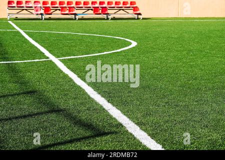 Grünes Kunstrasen und rote Spektratsitze auf einem kleinen Spielfeld. Stockfoto