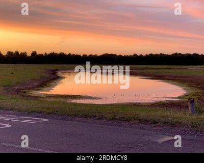 Dorney, Buckinghamshire, Großbritannien. 9. Juli 2023. Die Sonne geht über einem neuen Flutwassersee auf Dorney Common unter. Das Wasser der Themse darf überschüssiges Regenwasser in den nahe gelegenen Roundmoor Graben ableiten, und die Einheimischen, die im Dorf Eton Wick leben, mit Grundstücken, die zurück auf den Roundmoor Graben zurückgehen, klagen über den Gestank von Abwasser aus dem Wasser. Kredit: Maureen McLean/Alamy Stockfoto