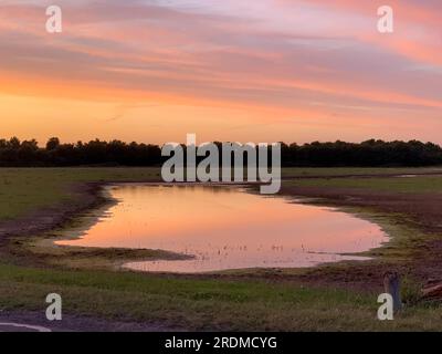 Dorney, Buckinghamshire, Großbritannien. 9. Juli 2023. Die Sonne geht über einem neuen Flutwassersee auf Dorney Common unter. Das Wasser der Themse darf überschüssiges Regenwasser in den nahe gelegenen Roundmoor Graben ableiten, und die Einheimischen, die im Dorf Eton Wick leben, mit Grundstücken, die zurück auf den Roundmoor Graben zurückgehen, klagen über den Gestank von Abwasser aus dem Wasser. Kredit: Maureen McLean/Alamy Stockfoto