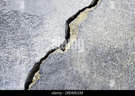 Großer Riss an der alten Putzwand. Lange Wicklungen, aufsteigender Riss in der Zementoberfläche eines alten Gebäudes. Speicherplatz kopieren. Selektiver Fokus. Stockfoto