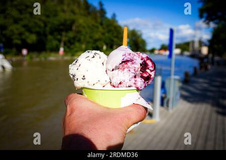 Eine gekürzte Hand, die Eiscreme gegen einen Kanal hält Stockfoto