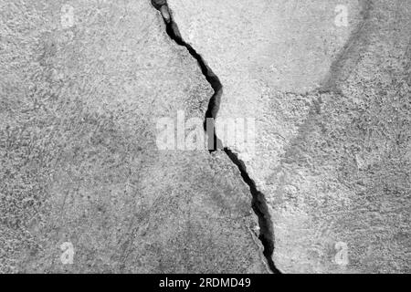 Großer Riss an der alten Putzwand. Langer Wicklungsriss in der Zementoberfläche eines alten Gebäudes. Schwarzweißfoto. Speicherplatz kopieren. Selektiver Fokus. Stockfoto