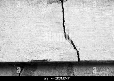 Großer Riss an der alten Putzwand. Langer Wicklungsriss in der Zementoberfläche eines alten Gebäudes. Schwarzweißfoto. Speicherplatz kopieren. Selektiver Fokus. Stockfoto