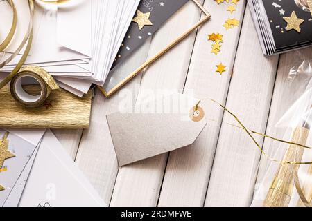 Schicke Geschenkverpackung und Anhänger mit goldenen Akzenten und Sternenformen. Elegante Geschenkverpackungsszene mit goldenen Sternen, gestreiftem Papier und leerem Geschenkanhänger Stockfoto