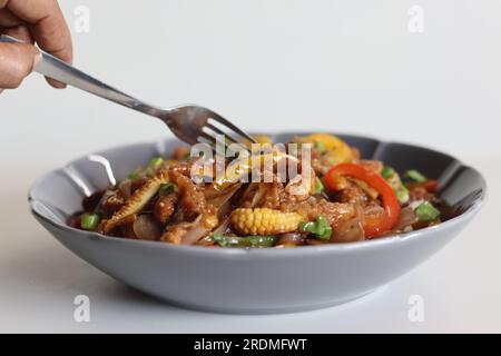 Babymais kalt. Ein chinesisches Indo-Gericht mit knackig gebratenem Babymais in einer scharfen Sauce mit sautierten Zwiebeln und Paprika. Aufnahme auf weißem Hintergrund Stockfoto
