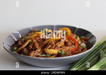 Babymais kalt. Ein chinesisches Indo-Gericht mit knackig gebratenem Babymais in einer scharfen Sauce mit sautierten Zwiebeln und Paprika. Aufnahme auf weißem Hintergrund Stockfoto