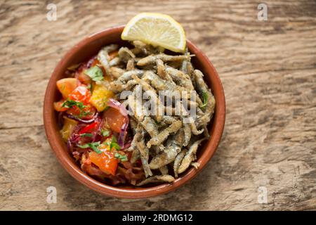 Frische Sprotten, Sprattus sprattus, die mit Mehl und Paprika überzogen wurden, bevor sie in Öl frittiert wurden. Sie werden mit einer gekochten Salsa serviert Stockfoto