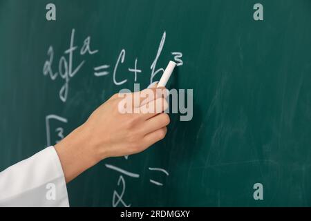 Lehrerin, die Mathematik-Formel auf der Tafel schreibt, im Klassenzimmer, Nahaufnahme Stockfoto