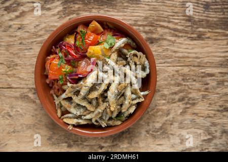 Frische Sprotten, Sprattus sprattus, die mit Mehl und Paprika überzogen wurden, bevor sie in Öl frittiert wurden. Sie werden mit einer gekochten Salsa serviert Stockfoto