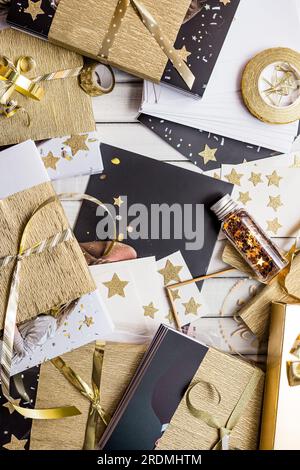 Schicke Geschenkverpackung und Anhänger mit goldenen Akzenten und Sternenformen. Elegante Geschenkverpackungsszene mit goldenen Sternen, gestreiftem Papier und leerem Geschenkanhänger Stockfoto