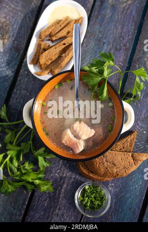 Blick von oben auf heiße Fischsuppe mit rotem Fisch und Grün auf einem Holztisch. Stockfoto