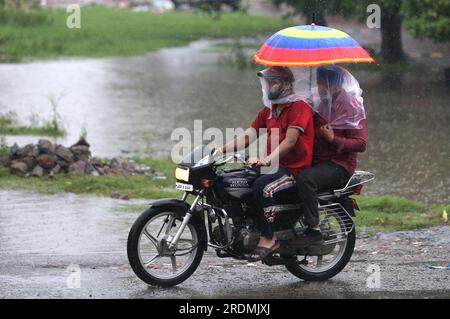 Amritsar. 22. Juli 2023. Die Menschen fahren mit einem Motorrad im Regen im Bezirk Amritsar im nördlichen indischen Bundesstaat Punjab, 22. Juli 2023. Kredit: Str/Xinhua/Alamy Live News Stockfoto