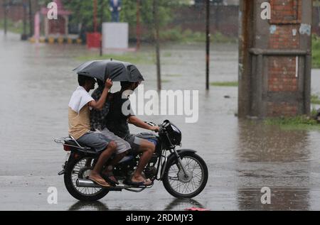 Amritsar. 22. Juli 2023. Die Menschen fahren mit einem Motorrad im Regen im Bezirk Amritsar im nördlichen indischen Bundesstaat Punjab, 22. Juli 2023. Kredit: Str/Xinhua/Alamy Live News Stockfoto