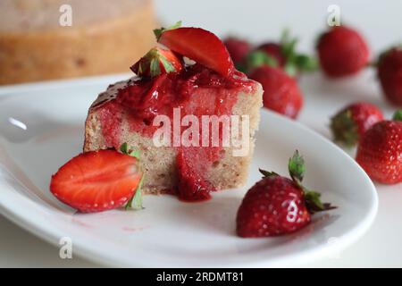 Ein Stück Erdbeerkuchen. Ein einfacher Teezeitkuchen mit frischem Erdbeerpüree. Serviert mit frisch geschnittenen Erdbeeren und Erdbeersauce. Schuss Stockfoto