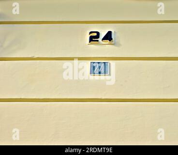 Nummer 24, 24, an einer hellgelben Wand. Stockfoto