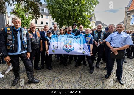 Ratingen, Deutschland. 22. Juli 2023. Mitglieder der Blauen Ritter, ein Motorradclub von Polizeibeamten, stehen bei der Gedenkfeier mit einer Flagge nach der Motorradsternfahrt zugunsten der Opfer des Angriffs in Ratingen im Mai, bei dem auch mehrere Notfallpersonal schwer verletzt wurden. Bei einer Explosion wurden 35 Menschen verletzt. Das Motto der Charity-Motorradfahrt lautet „Keine Gewalt gegen Rettungsdienste“. Kredit: Christoph Reichwein/dpa/Alamy Live News Stockfoto