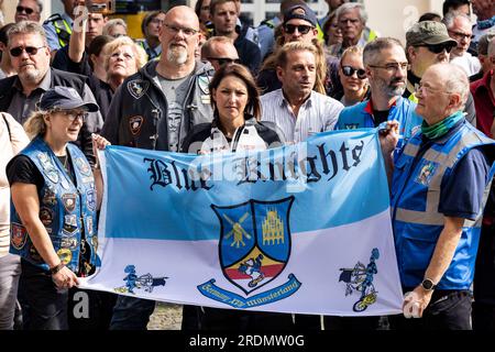 Ratingen, Deutschland. 22. Juli 2023. Mitglieder der Blauen Ritter, ein Motorradclub von Polizeibeamten, stehen bei der Gedenkfeier mit einer Flagge nach der Motorradsternfahrt zugunsten der Opfer des Angriffs in Ratingen im Mai, bei dem auch mehrere Notfallpersonal schwer verletzt wurden. Bei einer Explosion wurden 35 Menschen verletzt. Das Motto der Charity-Motorradfahrt lautet „Keine Gewalt gegen Rettungsdienste“. Kredit: Christoph Reichwein/dpa/Alamy Live News Stockfoto