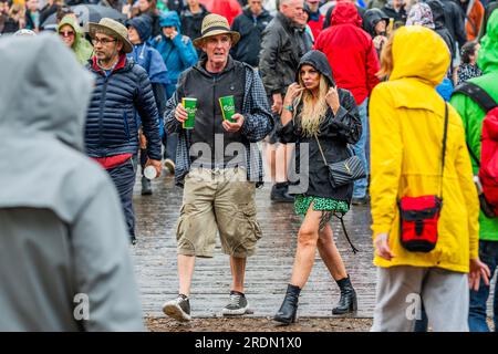 Henham Park, Suffolk, Großbritannien. 22. Juli 2023. Das Wetter ändert sich in langen Regen und die Menschen reagieren auf andere Weise - einige tragen Einweg-Ponchos, andere machen einfach weiter und werden nass, die meisten sind immer noch in guter Stimmung - das Latitude Festival 2023, Henham Park. Kredit: Guy Bell/Alamy Live News Stockfoto