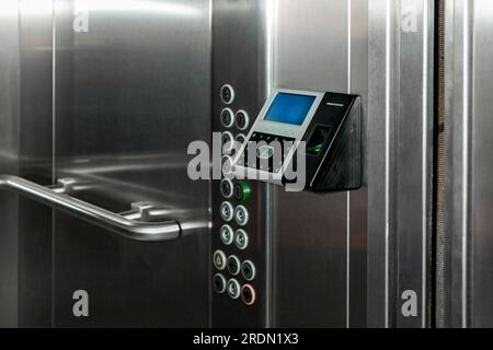 Das Terminal mit Fingerabdruck-Zugangskontrolle und Gesichtserkennung im Aufzug des Business Centers überwacht die Anwesenheit in Echtzeit Stockfoto