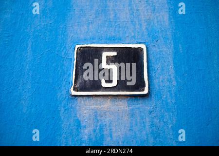 Elegante Nummer 5, fünf, dunkelblaues Schild auf hellblauem verwittertem Hintergrund. Stockfoto
