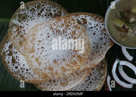 Reiskuchen mit Schnürsenkel serviert mit kerala-Hühnereintopf. Fermentierte Reispfannkuchen aus fermentiertem Reisteig und Kokosmilch. Lieblingsfrühstück Stockfoto