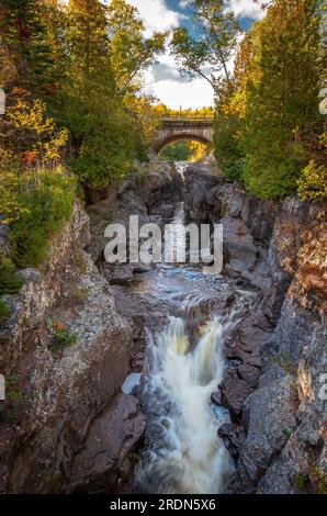 Dieser wunderschöne glen oder kleine Canyon, der unter dieser alten Brücke und dem Bogen floss, wurde am Nordufer von Minnesota inmitten der Herbstfarben gefunden. Stockfoto