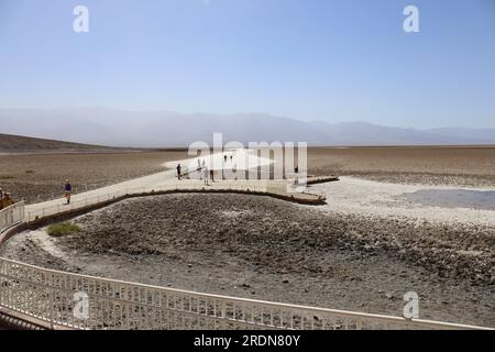 Touristen, die an einem nebligen Sommertag entlang der Promenade und auf die Sandebenen im Badwater Basin im Death Valley National Park, Kalifornien, USA, spazieren Stockfoto