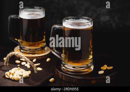 Becher mit Bier und salzigen Nüssen. oktoberfest-Atmosphäre, Hintergrund der Craft-Brauerei Stockfoto