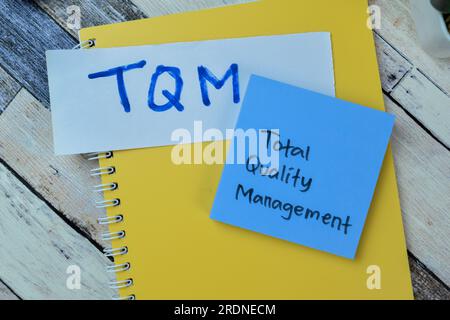 Konzept von TQM – Total Quality Management Schreiben Sie auf Haftnotizen, die isoliert auf einem Holztisch angebracht sind. Stockfoto