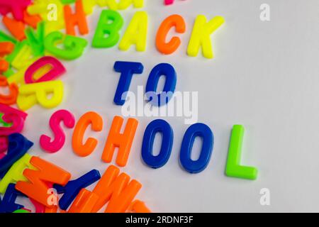 Dieses Aktienbild zeigt die Wörter „Back to School“ aus farbigen Buchstabenmagneten auf einem einfachen Hintergrund Stockfoto